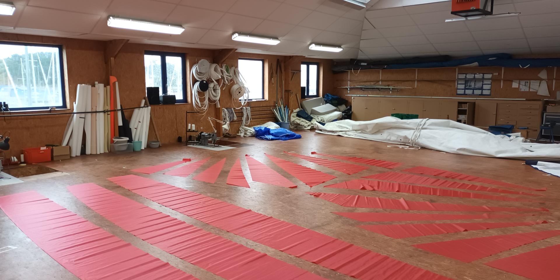 Parquet pour la fabrication de voile avec des voiles rouges dessus chez Fred Voile Atelier