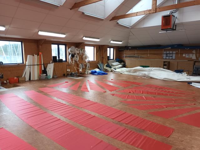 Parquet pour la fabrication de voile avec des voiles rouges dessus chez Fred Voile Atelier