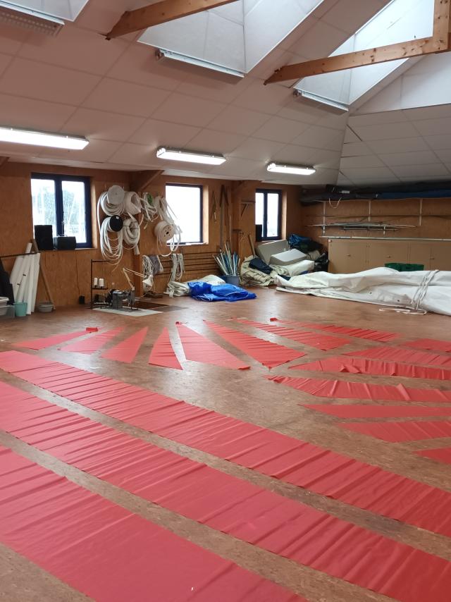 Parquet pour la fabrication de voile avec des voiles rouges dessus chez Fred Voile Atelier